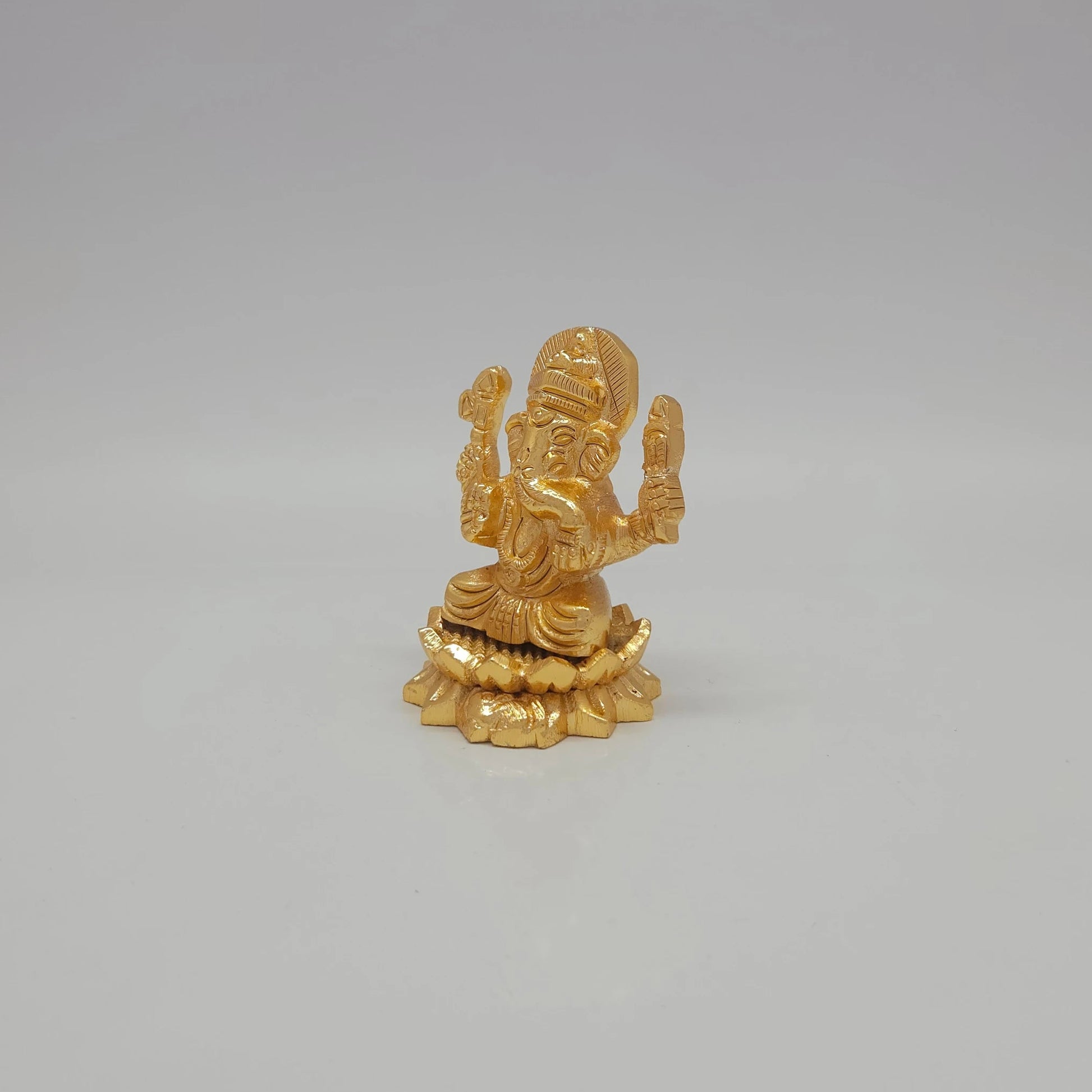 Left 45-degree angle profile of the glossy gold powder-coated brass Ganesha figurine highlighting its 120g weight