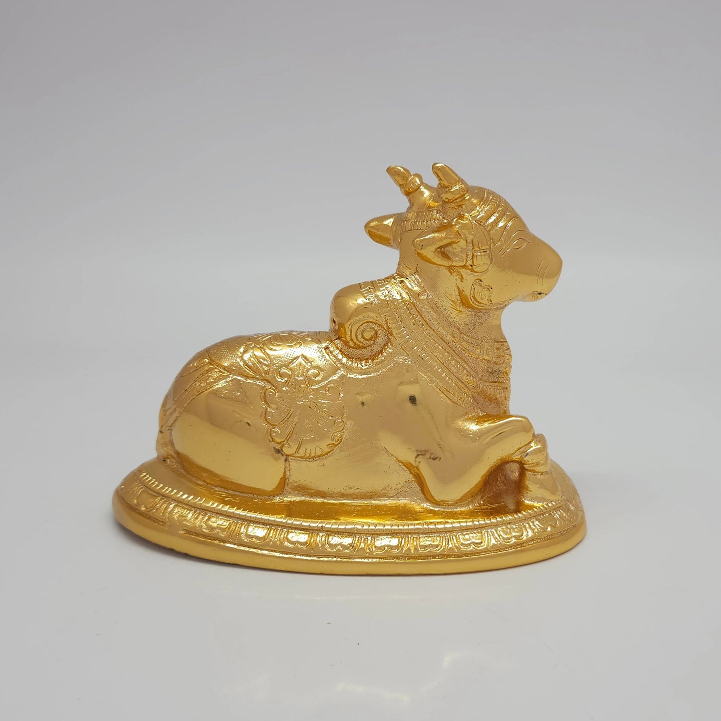 Rear view highlighting the textured saddlecloth patterns and uniform gold mirror finish of the 975g decorative brass bull.