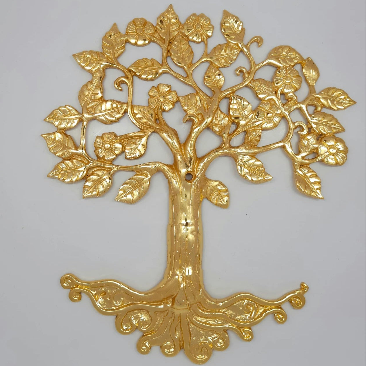 Close up macro shot of premium brass kalpavriksha tree wall panel showing chiseled leaves and flowers
