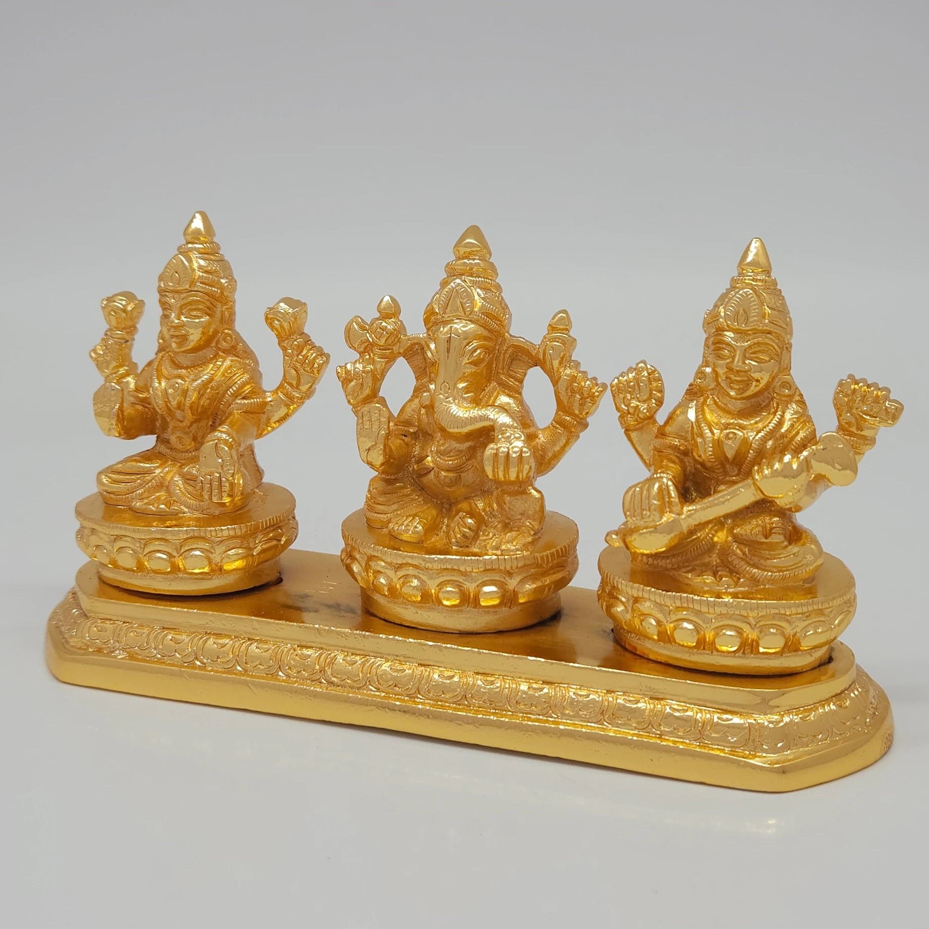 Left 45-degree angle profile emphasizing Goddess Lakshmi's lotus details, Ganesha's center posture, and the ornate tiered base borders.