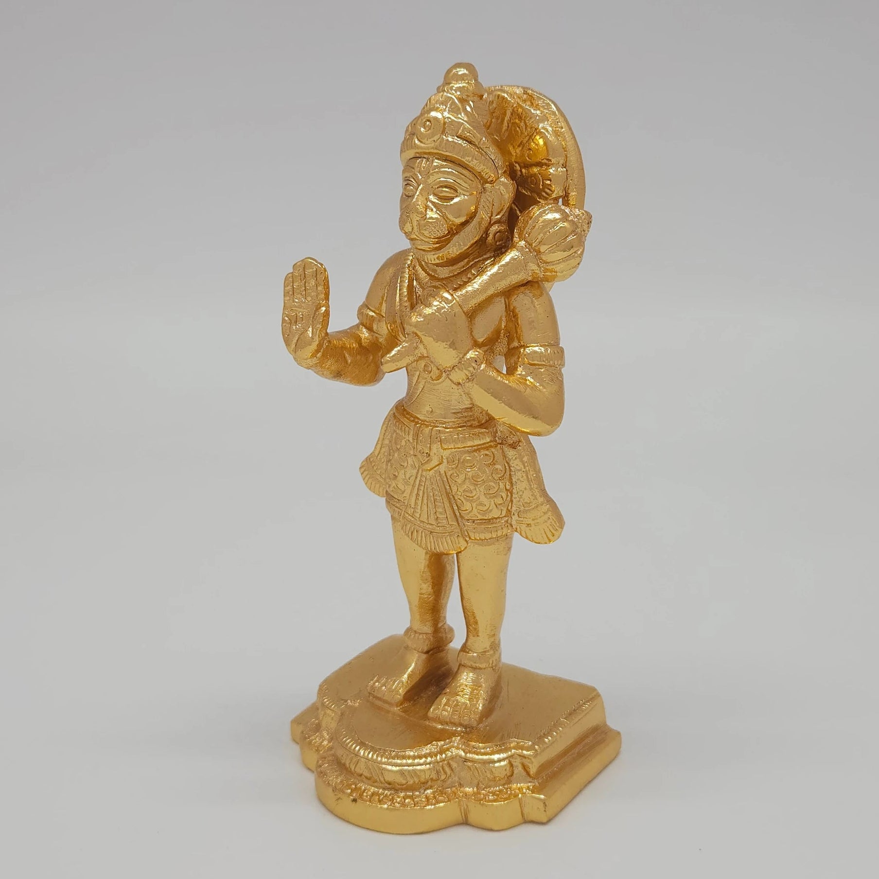 Left 45-degree angle profile emphasizing Hanuman's face structure, the grip on the gada mace, and the ornate tiered base borders