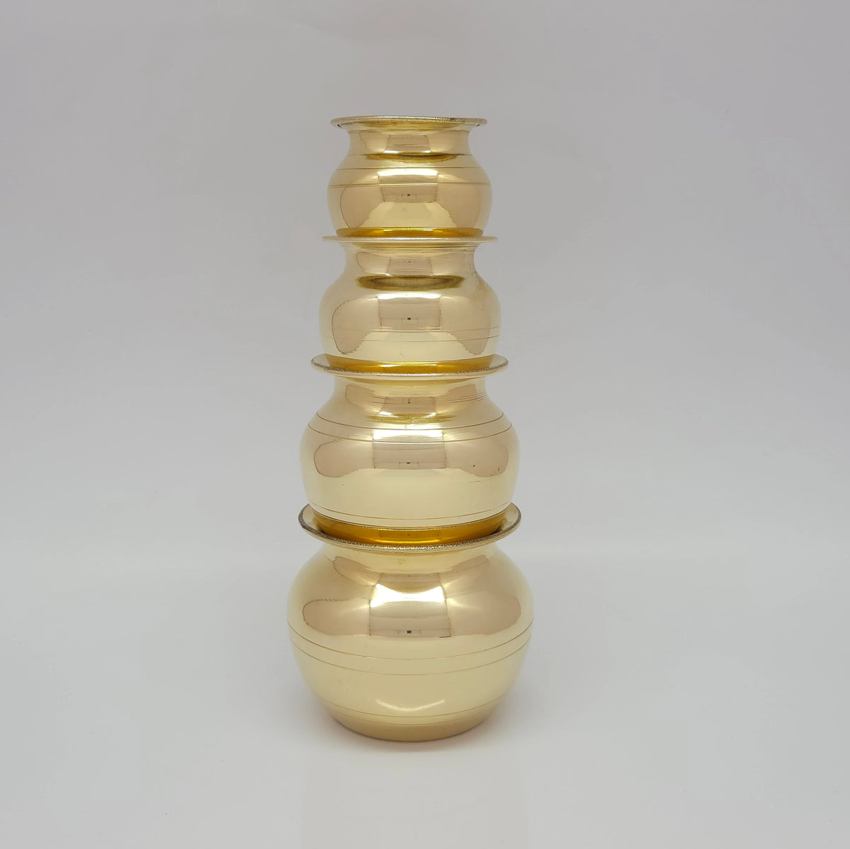 Studio shot of the brass pots stacked safely on top of each other in two dynamic pairs showing the nesting capability and rim stability of our traditional design.