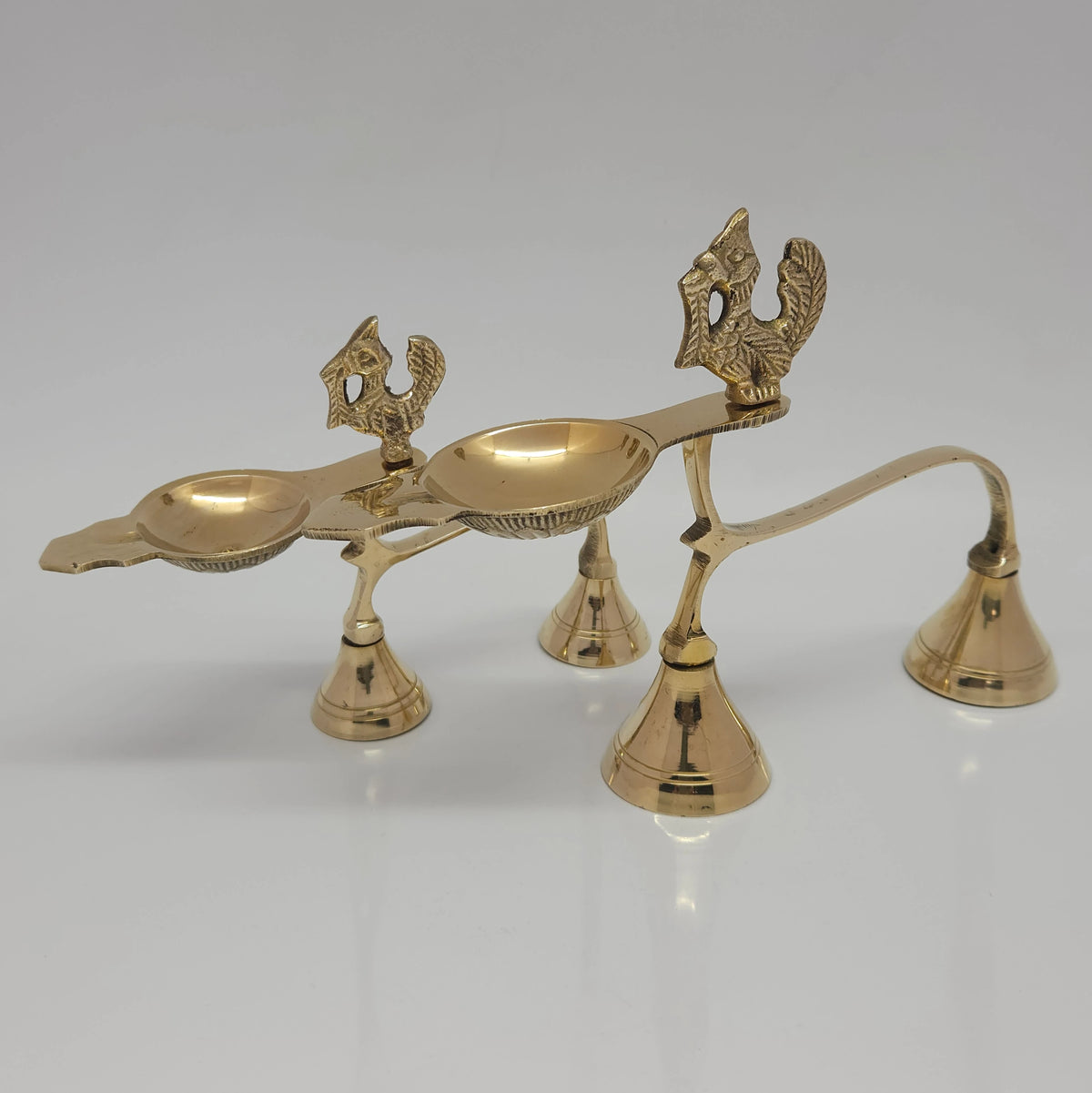 Front perspective view of the small and big variants of the pure brass handheld Annam aarti lamps placed together to show the height and length differences.