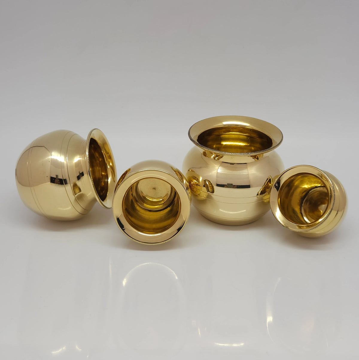 Balanced vertical stack of all four graduating pure brass pots forming a single tight tower to illustrate how seamlessly the nesting Aduku set stores away.