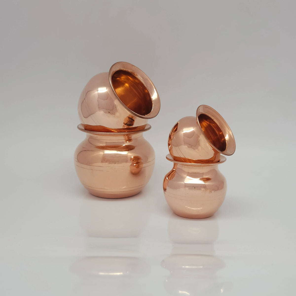 Studio profile view of the pure copper ritual pots stacked securely on top of each other in two vertical pairs to demonstrate the sturdy rim thickness and nesting design.