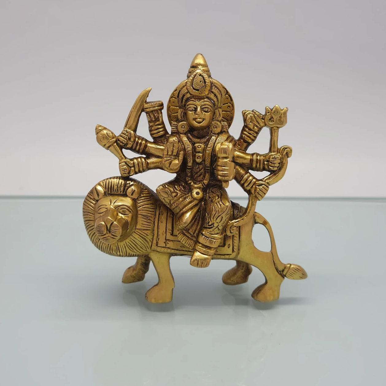 Front view of the 14.5cm antique solid brass Ashtabhuja Durga statue riding her lion with eight arms holding weapons for Navaratri pooja.