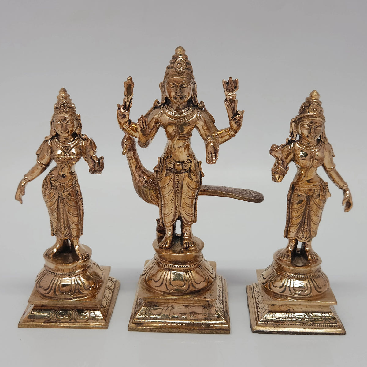 A close up frontal photograph of the Swamimalai Panchaloha Murugan trio emphasizing the traditional casting work on the crowns and garments.