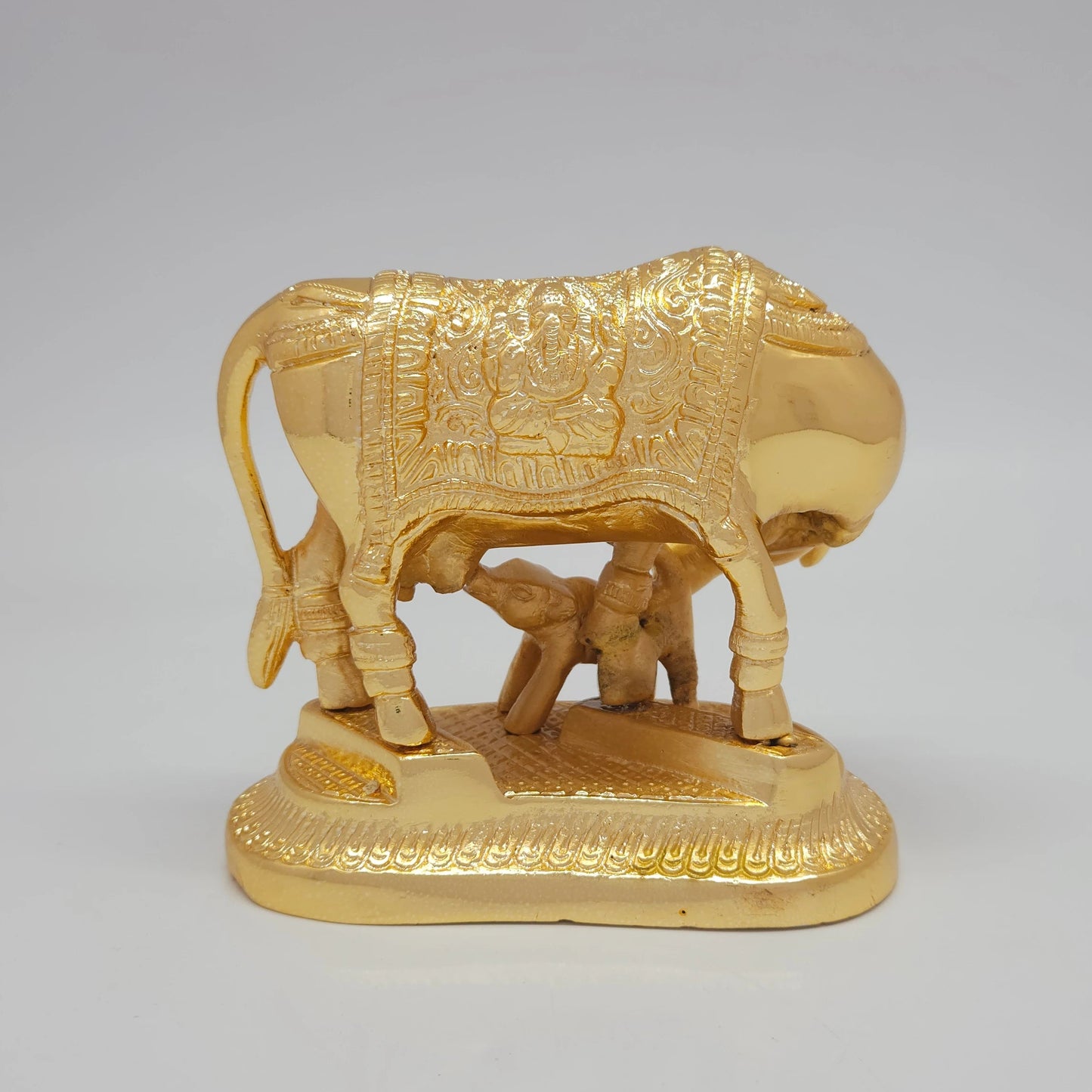 Rear view showcasing the detailed contours of the cow's tail, hindquarters, and the elegant Ganesha engraving on the back side of the saddlecloth.