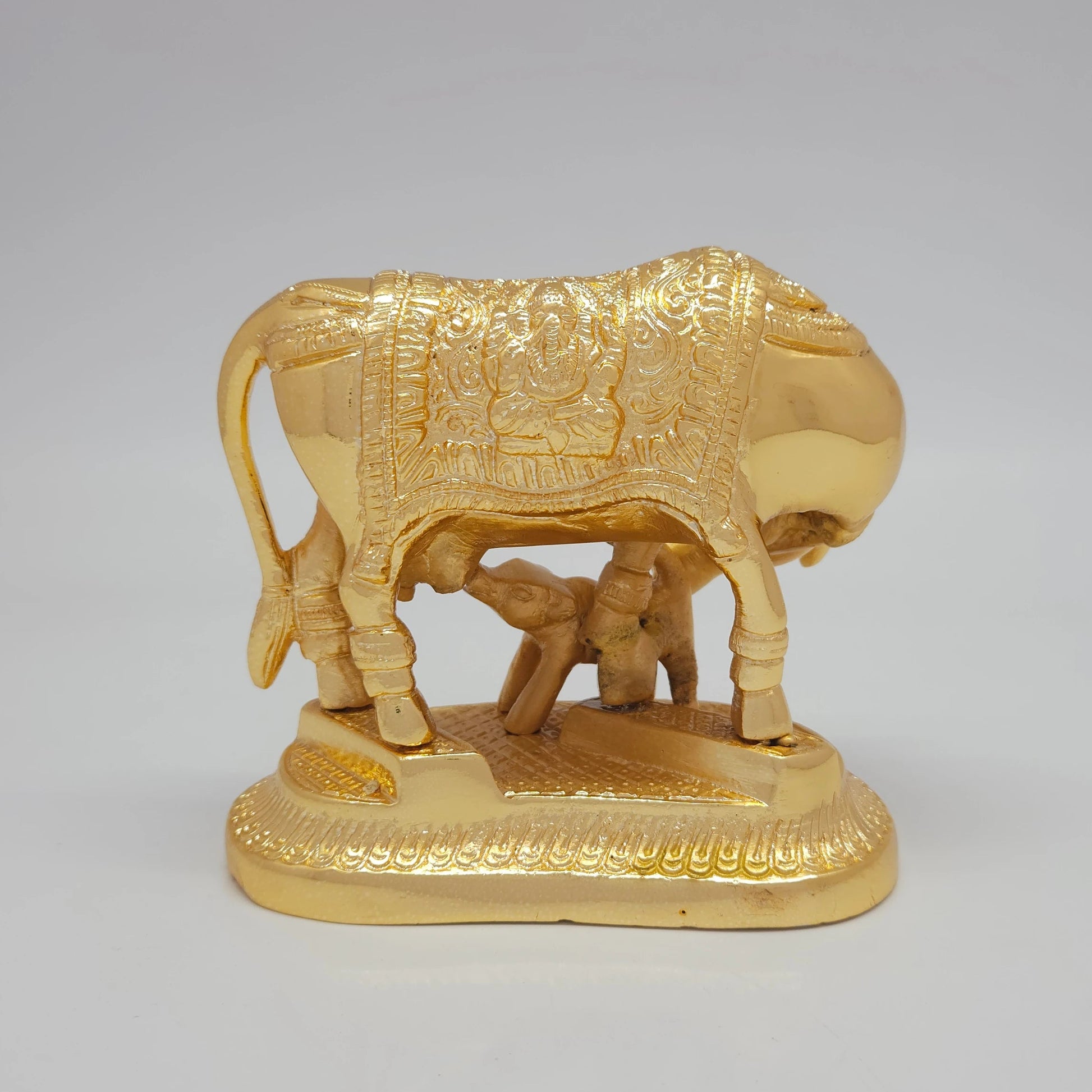 Rear view showcasing the detailed contours of the cow's tail, hindquarters, and the elegant Ganesha engraving on the back side of the saddlecloth.