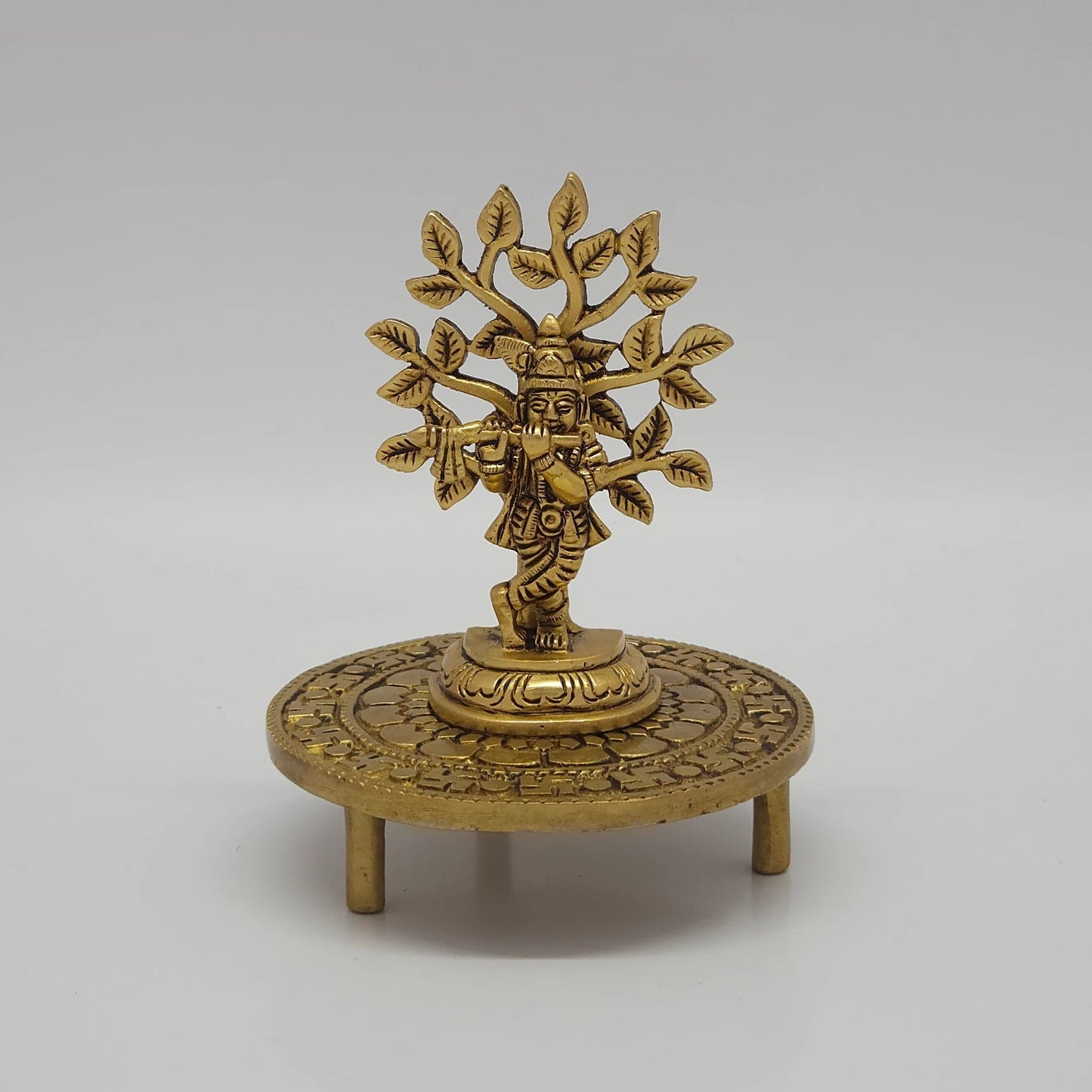 Decorative application sample showing a brass Kalpavriksha tree statue placed elegantly on top of the antique brass tripod chowki pedestal