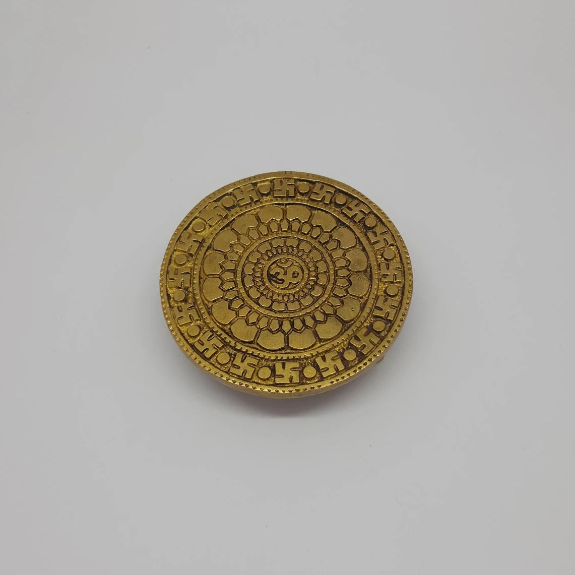 Top view of the 10cm antique solid brass circular Chowki pedestal showing the central Om symbol, lotus layers, and Swastika border for daily puja rituals
