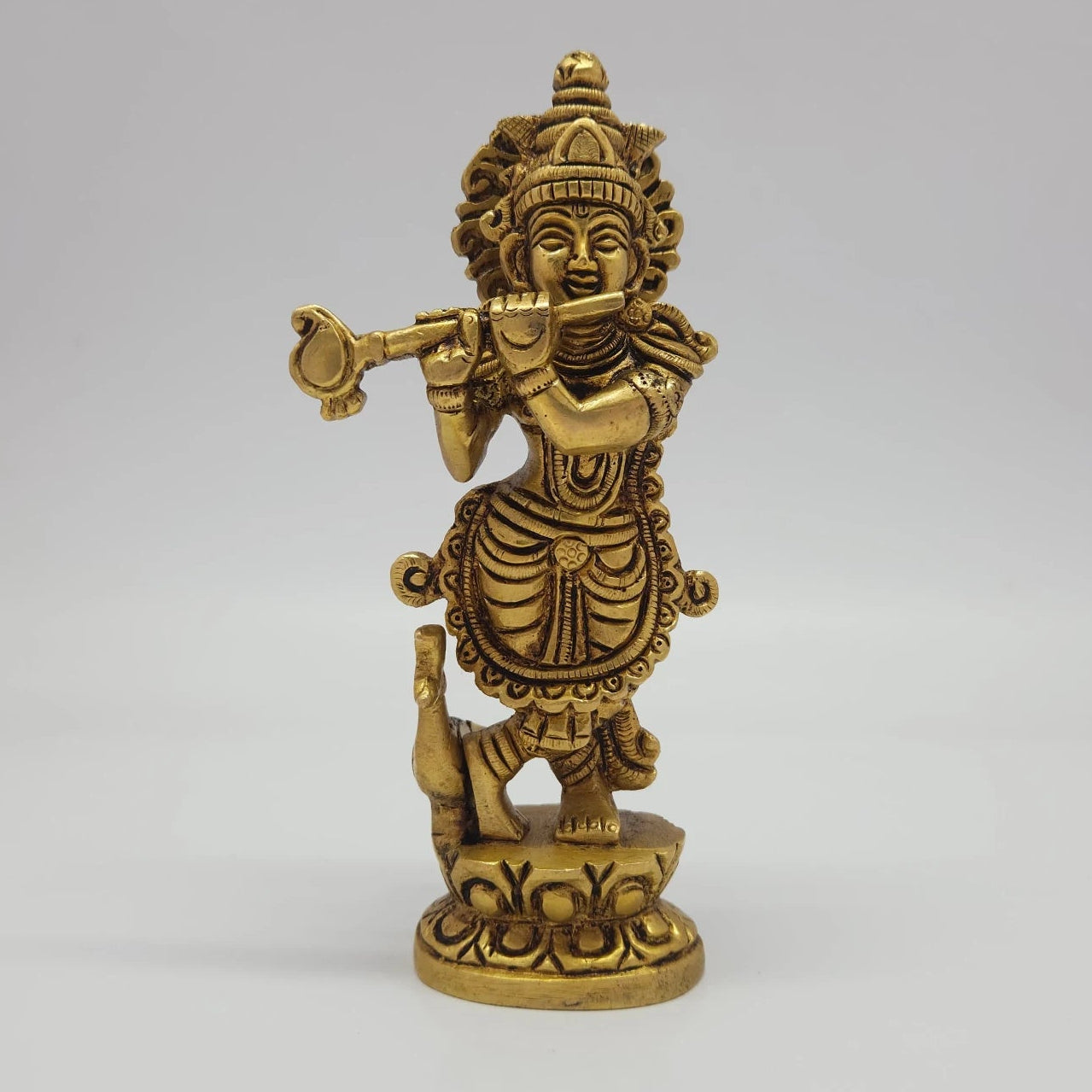 Front view of the 18cm antique solid brass Tribhanga Krishna statue with flute and peacock on a lotus base for daily pooja rituals.