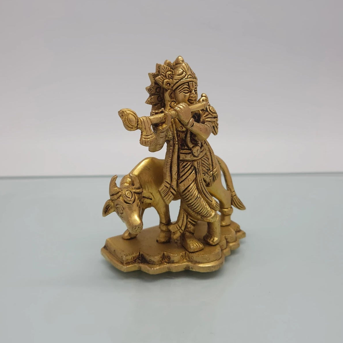 Right 45-degree perspective highlighting the fine features of the cow's lowered head, Krishna's profile smile, and the back leg alignments.