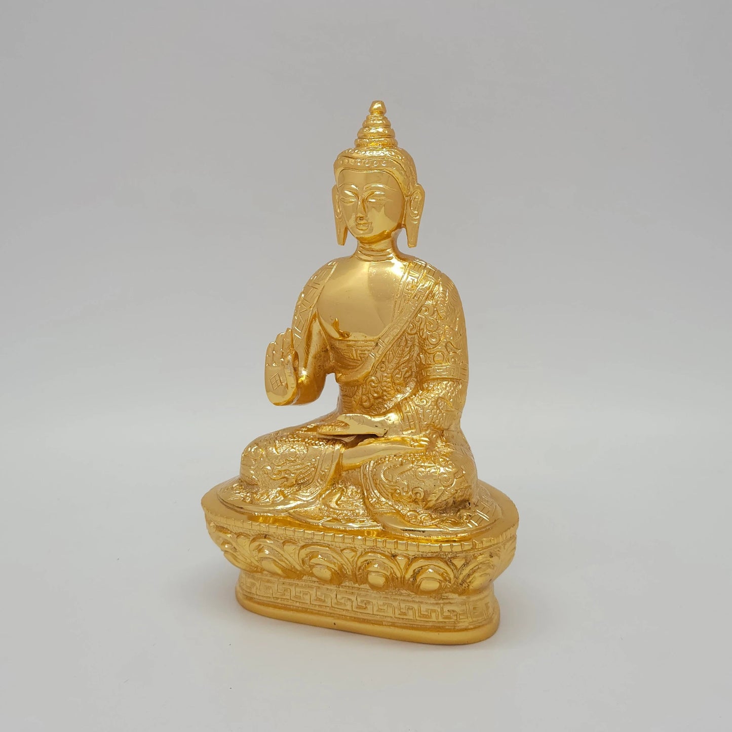 Left 45-degree angle profile of the high-gloss gold powder-coated Buddha brass figurine highlighting the intricate pedestal engravings
