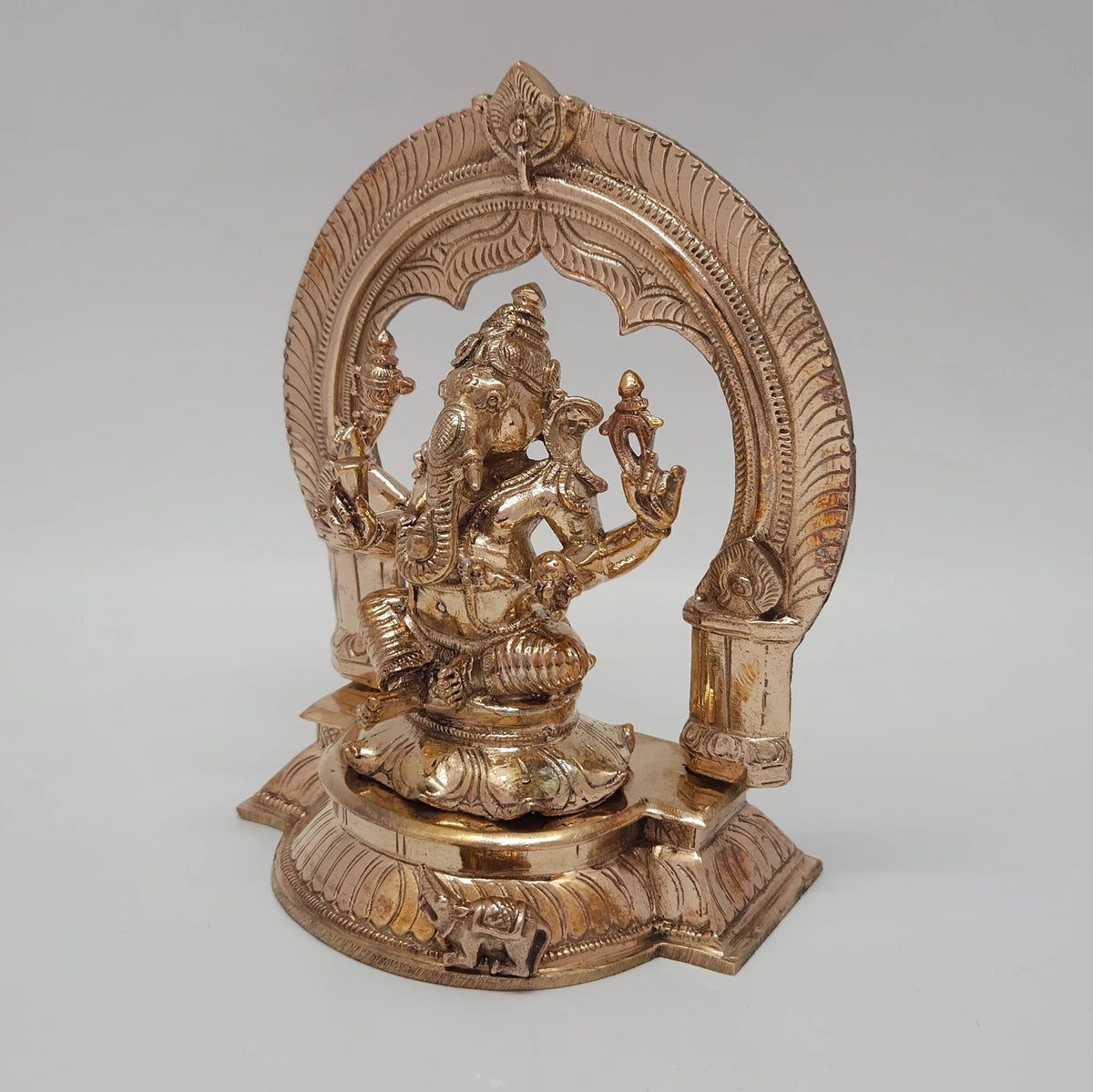 High three-quarter front view highlighting the detailed hand-chiseled facial features, trunk alignment, and glossy gold luster of the five-metal Vinayagar statue.