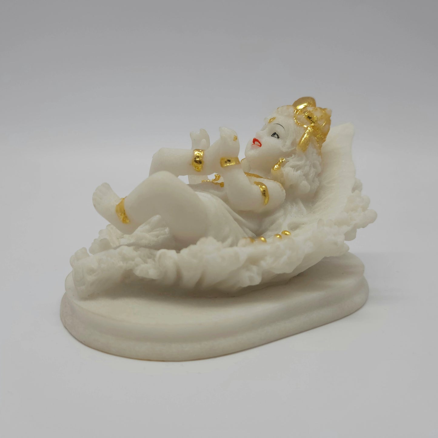 Front right perspective of the 3-inch baby Krishna statue demonstrating the clean details of the leaf veins and the solid pedestal.