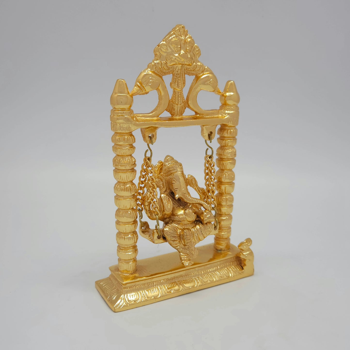 Three-quarter right angle view of the anti-tarnish gold powder-coated brass swinging Ganesha idol showing the depth of the temple pillars.