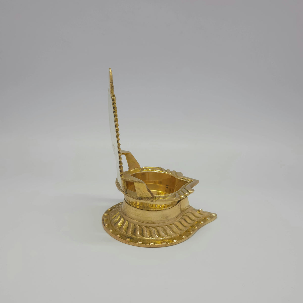 Side profile perspective view of the 360g brass Siluvai Vilakku showing the thin back plate frame and the front spout nose layout.