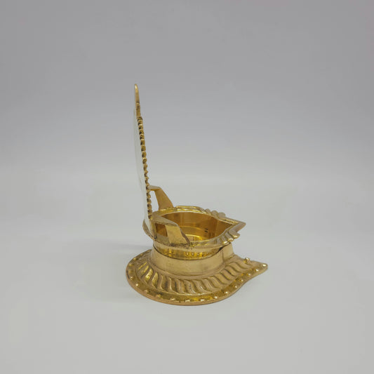 Side profile perspective view of the 360g brass Siluvai Vilakku showing the thin back plate frame and the front spout nose layout.