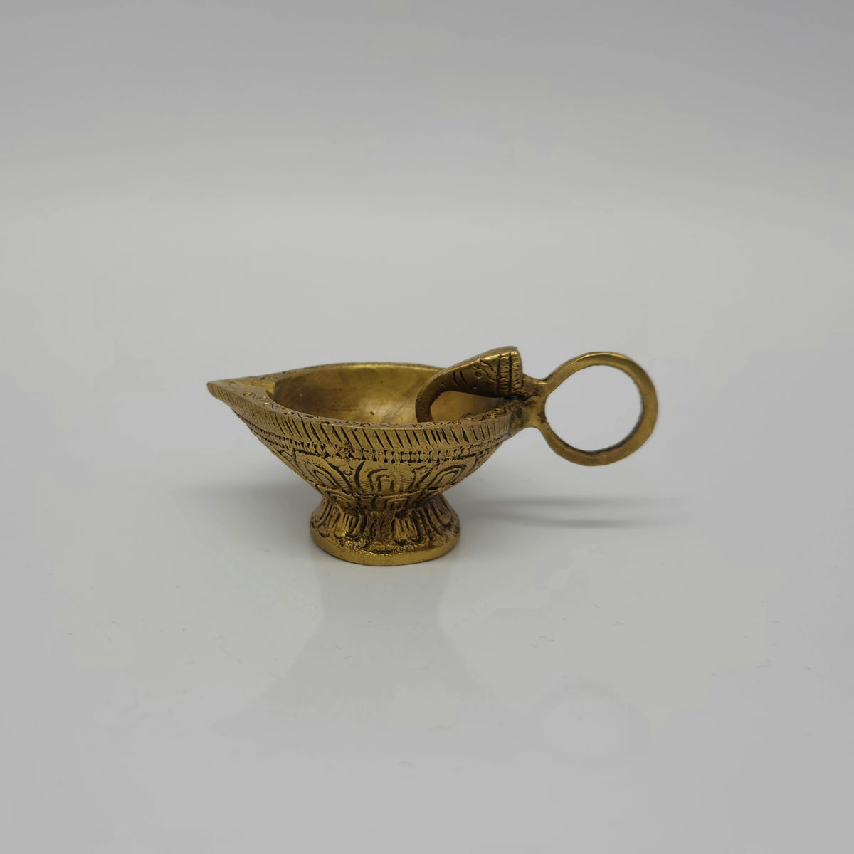 Side profile view of the 9.5cm brass handheld aarti diya showing the small elephant head design between the lamp cup and the ring handle by Sri Swaminathan and Co.