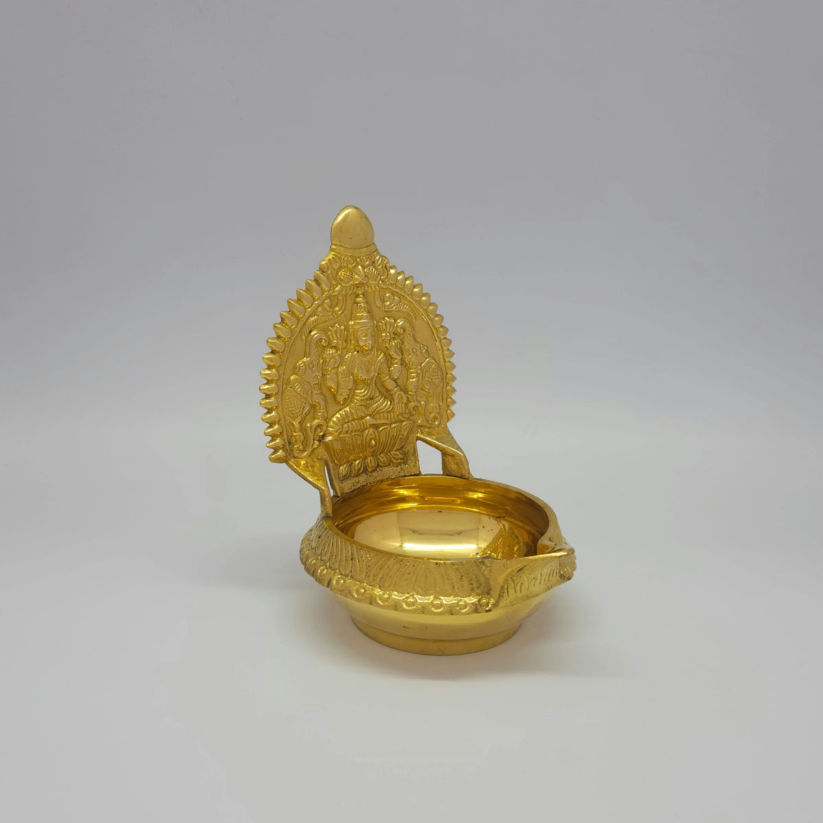 Three-quarter front right perspective view of the brass Kubera Gajalakshmi deepam highlighting the deep 150ml capacity basin.
