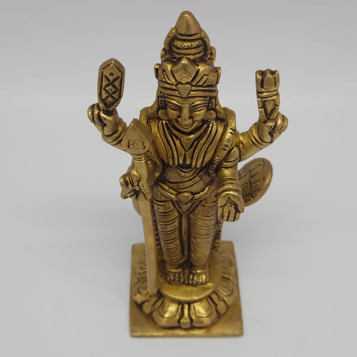Close up front perspective view highlighting the detailed hand chiseled weapon attributes and traditional crown markings of the brass Kumara Skanda statue