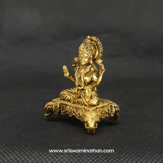 Three-quarter front left perspective view of the 5cm solid brass Lakshmi icon on a four-legged pedestal showing a durable dust-resistant surface needing only gentle liquid wipes.