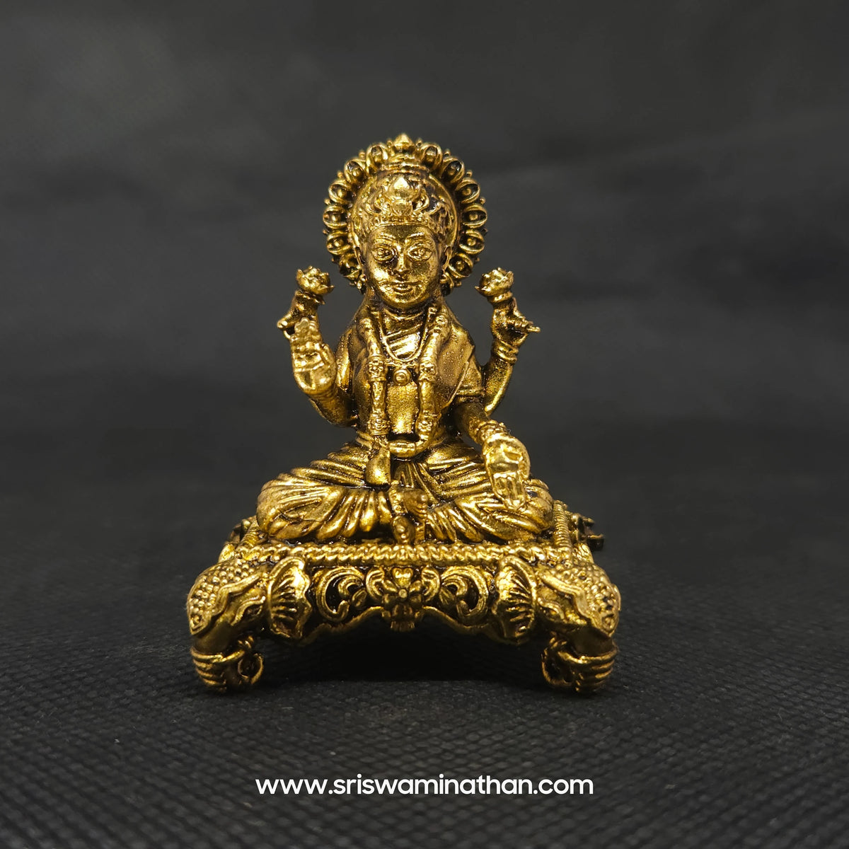 Straight front profile view of the 5cm premium brass Lakshmi statue on a floral elephant head pedestal featuring an easy-to-clean low maintenance golden finish by Sri Swaminathan and Co.