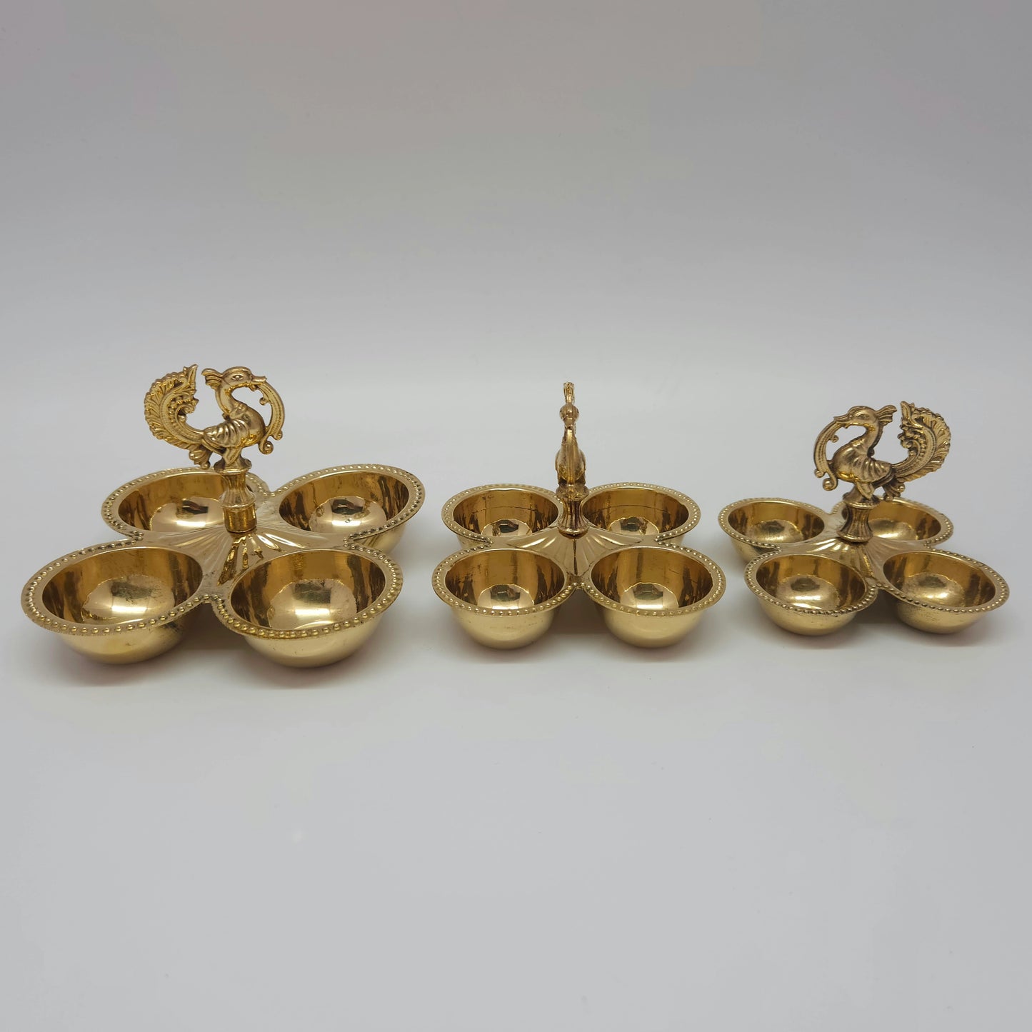 Small, medium, and big size variations of the multi-purpose brass peacock 4-cup holder placed side by side.