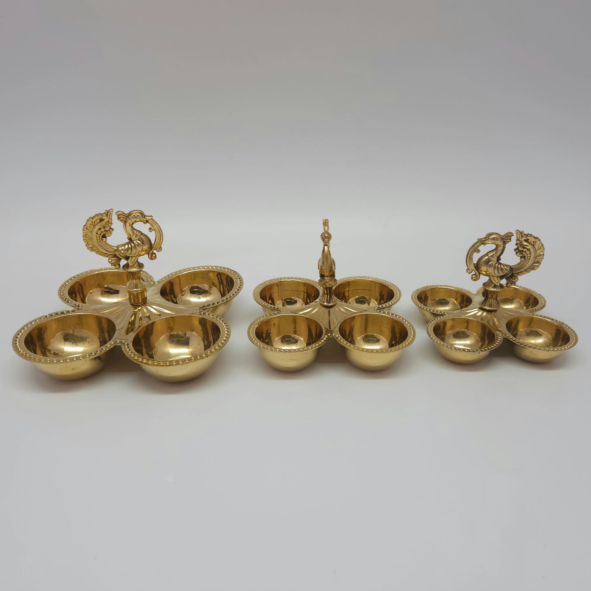 Small, medium, and big size variations of the multi-purpose brass peacock 4-cup holder placed side by side.
