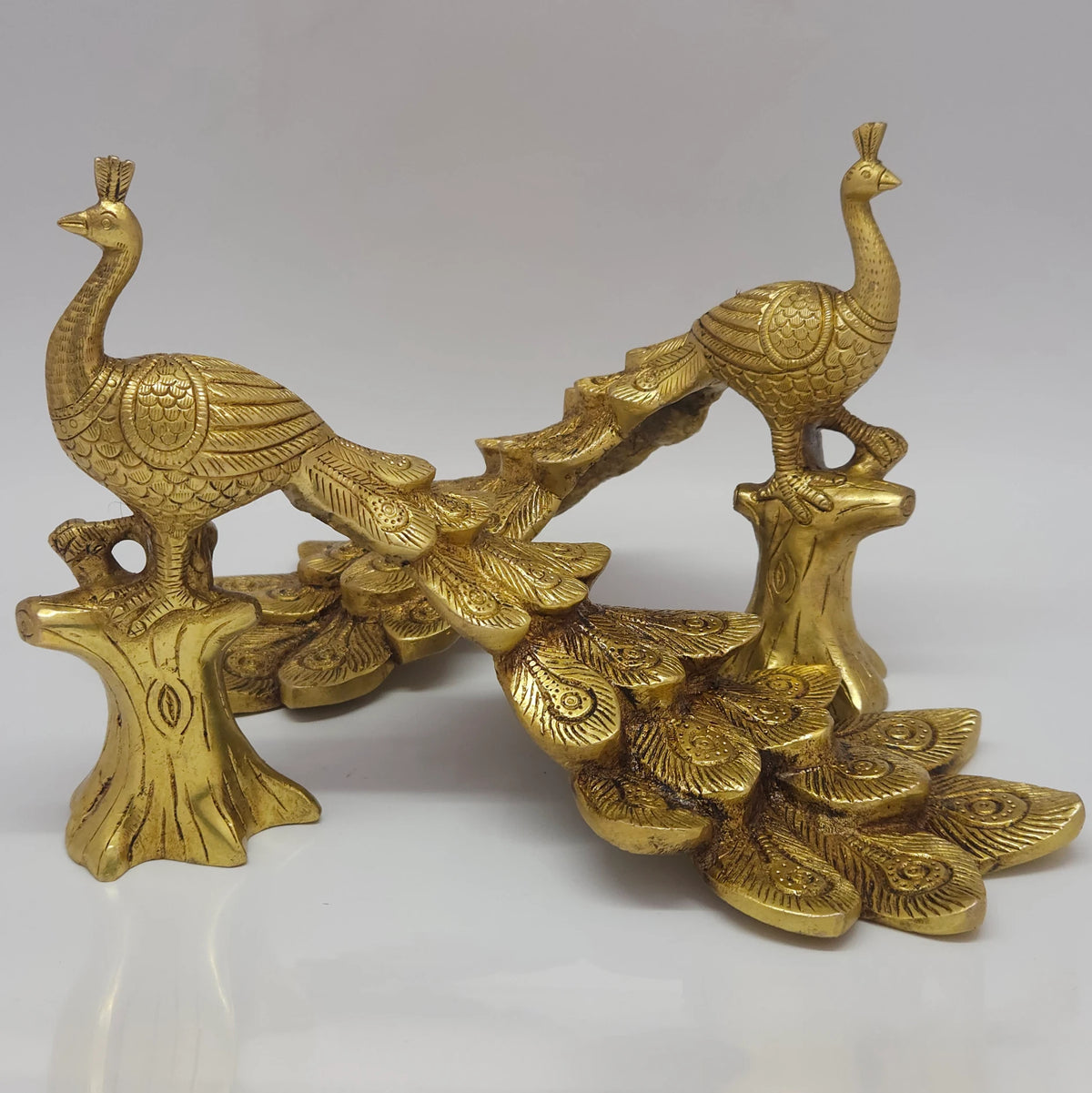  Front perspective view demonstrating a styling decor idea with two individual brass peacock statues arranged symmetrically together to frame an interior console.
