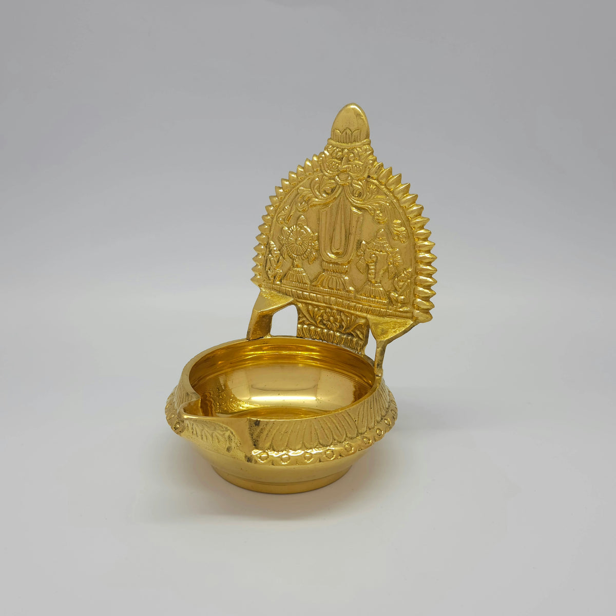 Three-quarter front left perspective view of the solid brass Perumal Namam lamp showing the sharp vertical ridge lines on the outer rim.