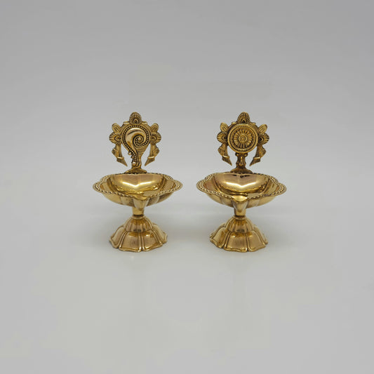 Straight front view of the premium brass Shanku Chakra pedestal Vishnu altar vilakku pair displaying the balanced conch and discus emblems by Sri Swaminathan and Co.