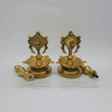 Angled view displaying the brass Shanku and Chakra lamp heads unscrewed from their 25cm standing pedestal stems to showcase the modular threads.