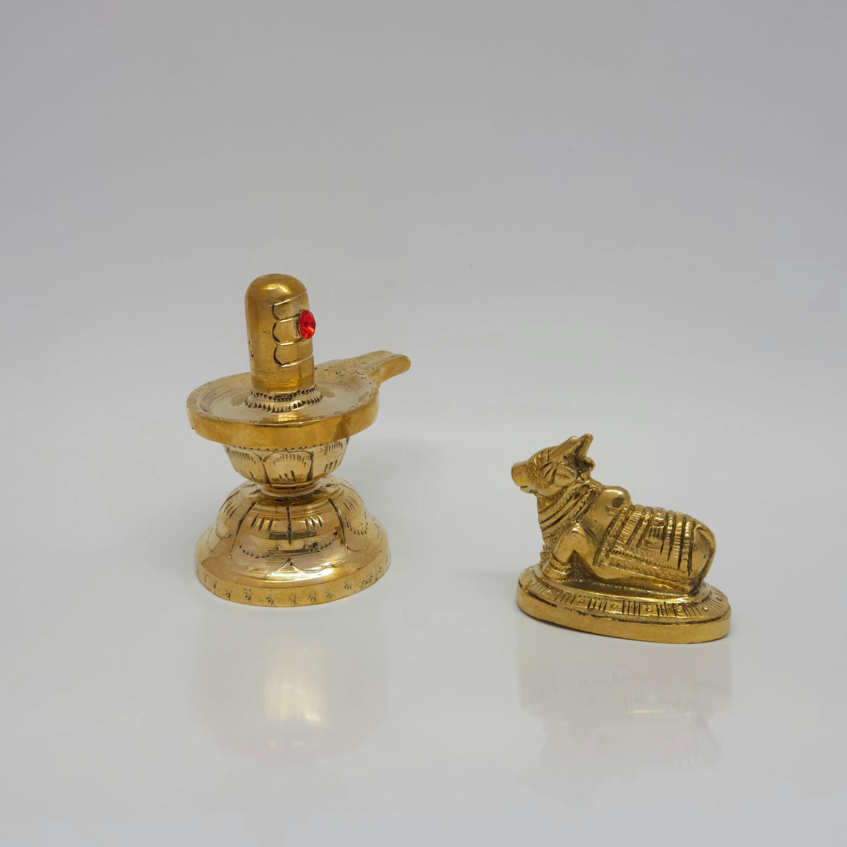 Wide straight front profile view of the 9cm handcrafted solid brass Shivalingam next to the 5.1cm seated Nandi bull on a white background by Sri Swaminathan and Co