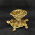 Three-quarter front right perspective view of the brass Tortoise deepam showcasing the pointed wick spout and detailed leg paw carvings.