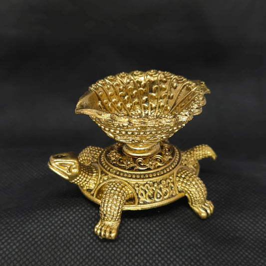 Three-quarter front right perspective view of the brass Tortoise deepam showcasing the pointed wick spout and detailed leg paw carvings.