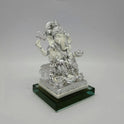 Left three-quarter angle view of the chrome silver painted resin Ganpati idol showcasing the thick green-edged rectangular glass stand