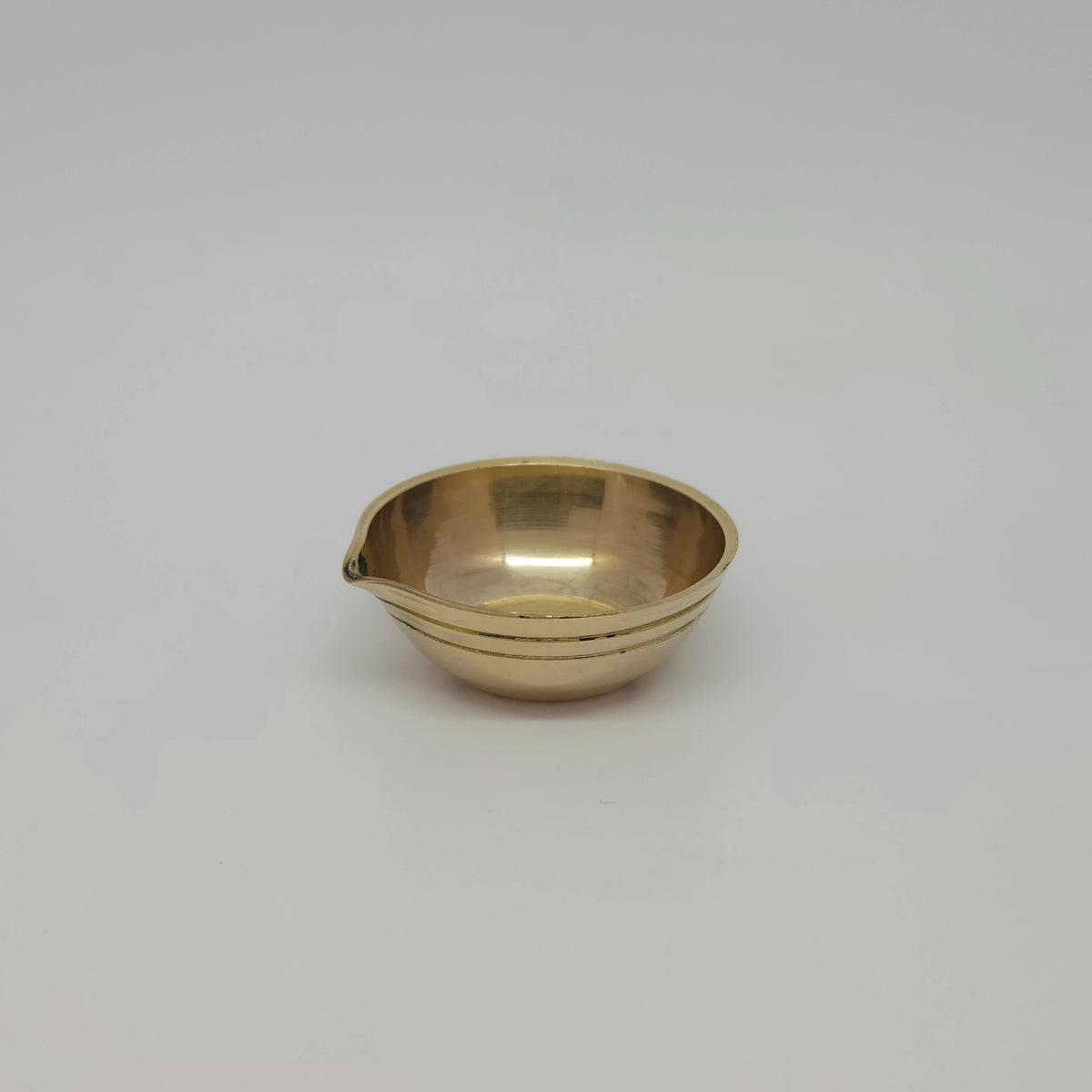 Left side perspective view of the 1.5cm tiny brass agal vilakku highlighting the smooth high-gloss mirror finish.