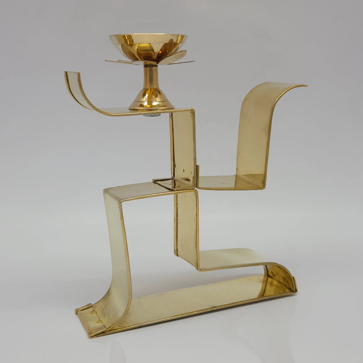 Side angle photo of pure brass Swastik shape pooja deepam showing the thickness and golden metal finish.