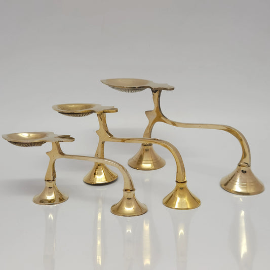 Front view of three size variants of pure solid brass long-handle arati oil lamps arranged together on a plain white surface.