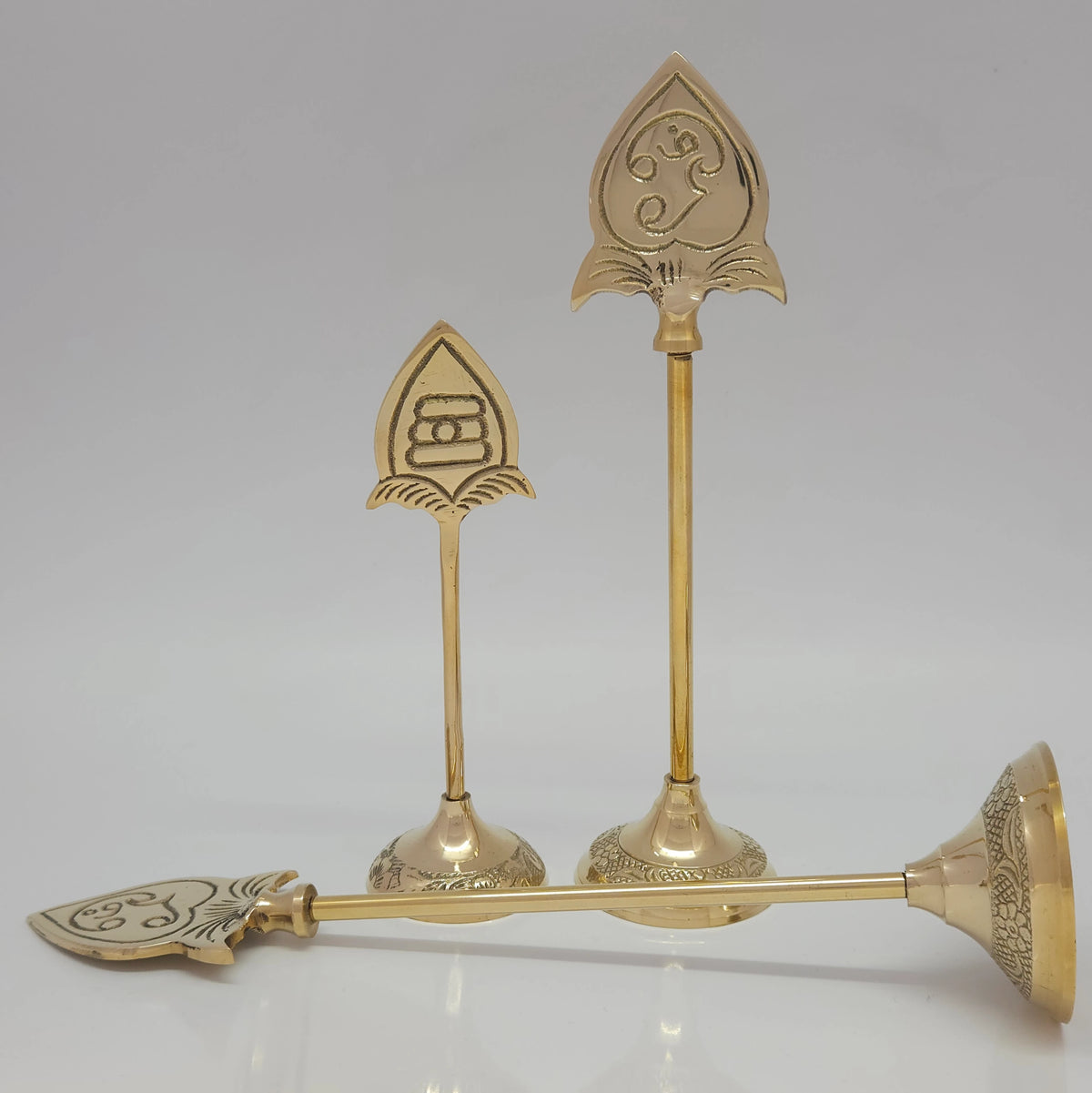Front view of three pure brass Murugan Vel stands showing two standing upright and one disassembled horizontally on a white background to highlight the detachable pieces.