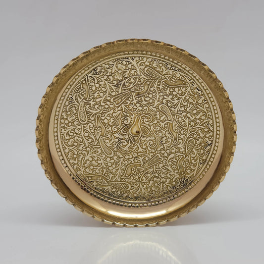Straight front view of the larger pure brass engraved puja plate showing the highly detailed bird and flower plant design with a wavy scalloped border.