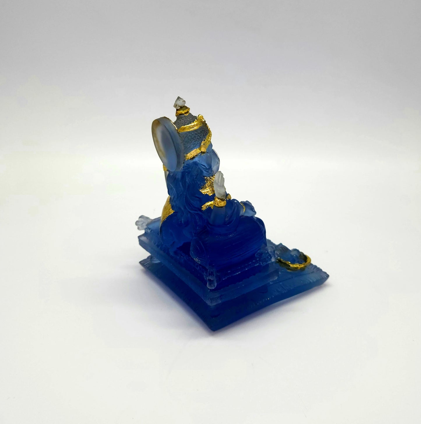 Top right angle view of the semi-transparent frosted blue Ganesha sculpture showing his divine weapons and side profile.