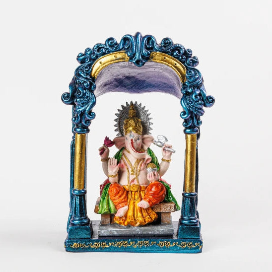 Hand-painted multi-color Lord Ganesha resin statue seated under a royal blue and gold pillar temple archway by Sri Swaminathan and Co.