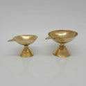 Front presentation view displaying two different variant sizes of the identical brass single-spout pedestal lamps standing side-by-side on a reflective surface.