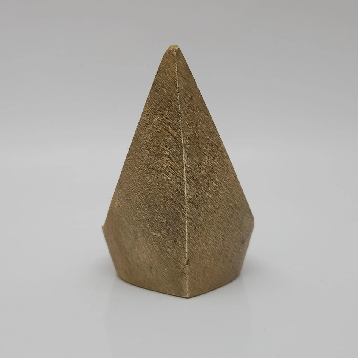 Direct straight back view of the eight centimeter solid brass mada vilakku demonstrating the smooth triangular rear finish and flat base contours.