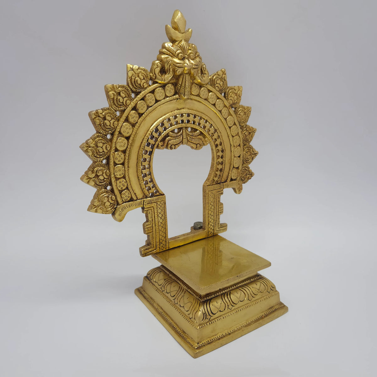 Three-quarter front left perspective view of the eleven inch brass prabhavali singhasan throne highlighting the deep square seat platform and base molding thickness