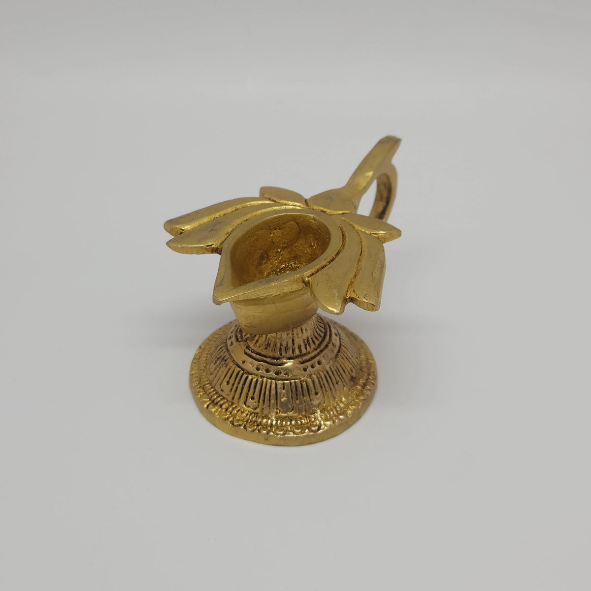 Three-quarter front right perspective view of the four centimeter brass lotus handled lamp showcasing the pointed spout wick groove and round pedestal base