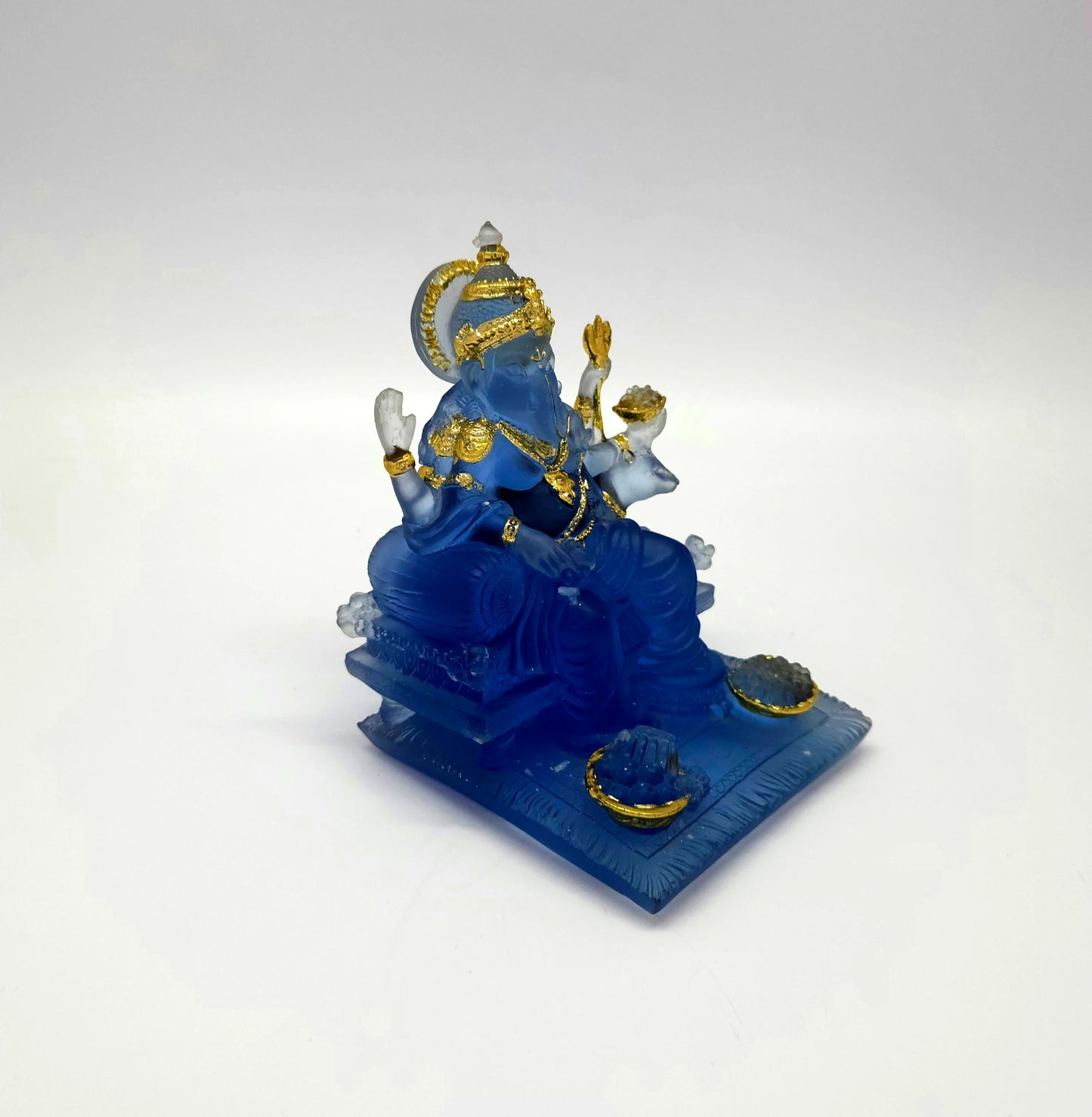 Lower three-quarter right perspective view of the translucent blue resin Ganesha idol sitting comfortably on his throne.
